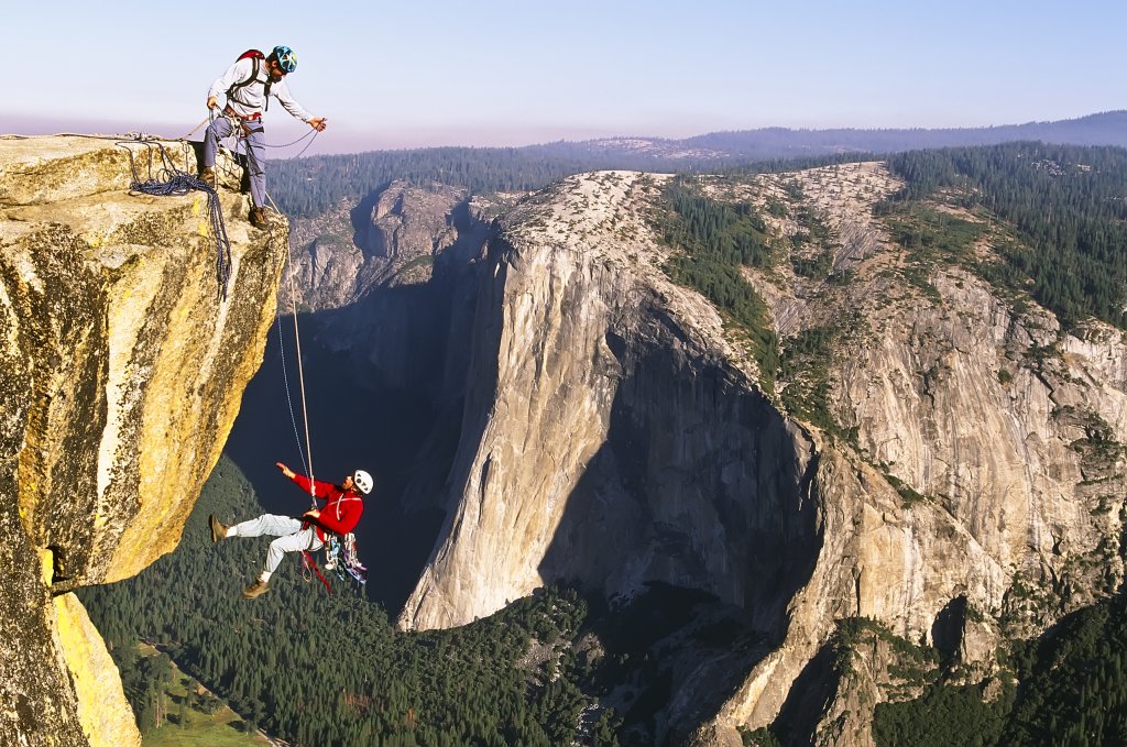 Team of climbers reaching the summit of a rock pinnacle.