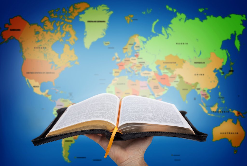 The Great Commission Hand showing the Holy Bible against world map